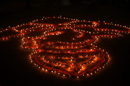 Traditional earthen lamps beautifully setup in a design on a lawn at night, during Diwali festival in India.の写真素材