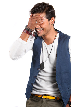 A young Indian guy embarrassed about a joke, on white studio background.の写真素材