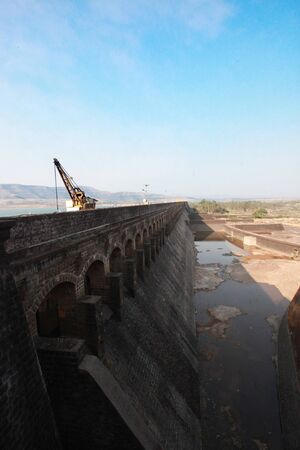 A long stretch of a strong but old dam wall made of black stones .の写真素材