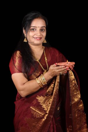 A beautiful Indian woman smiling holding in Diwali due to happiness in Diwali, on black studio background.の写真素材