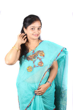 A beautiful middle aged Indian woman in saree showing her earring, on white studio background.の写真素材