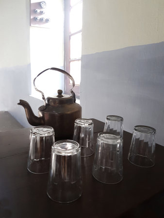 A vintage teapot made of brass with small glasses, used for tea served in India.