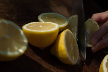 Sharp knife slicing lemon into quarters for fresh lemonade