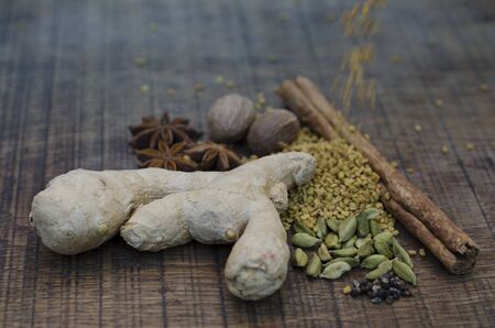 Fenugreek seeds, tumbling onto ayurveda spices, fresh ginger root, cardamom pods and seeds, a...