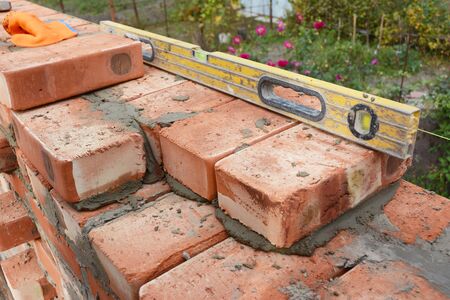 Bricklaying with Spirit Level to Check New Red Brick  House Wall Outdoor.  Basic Bricklaying.