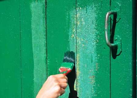 How to Paint Wooden Old Door. Worker hand with brush painting wooden door.の写真素材