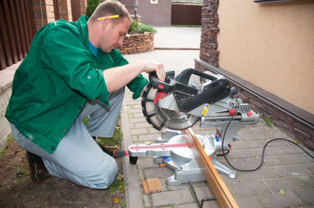 KYIV, UKRAINE - MARCH 3, 2017: Contractor cutting Skirting Board for parquet house flooring with grinder.のeditorial素材