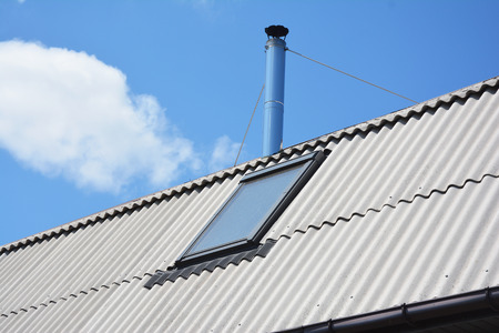 Attic skylight roof window on the asbestos house roof. Roofing construction.の写真素材