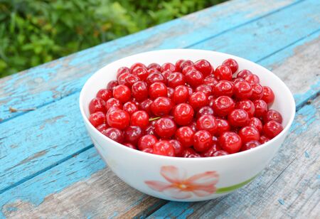 Ripe Cherries. Cherry on blue wooden background. Fresh Cherries in color bowl. Red cherry as healthy...
