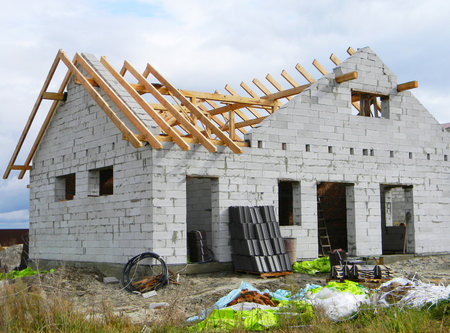 House roofing construction with wooden trusses. Timber roof trusses building. Wooden Roof Frame House Construction. Construction site.のeditorial素材