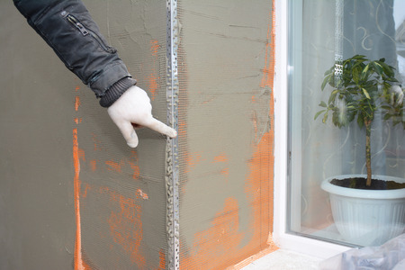 Building contractor plastering wall, stucco after rigid insulation in window sill problem area.の写真素材