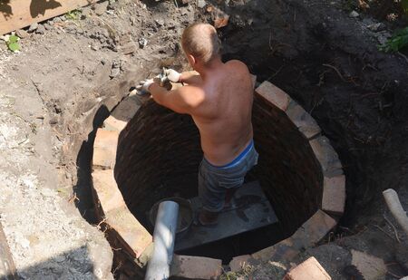 Builder bricklaying new septic tank. Sewer tank hole installation for house outdoors