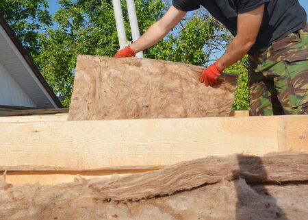 Roof Insulation. Roofer Installing House Roof Thermal Insuation with Mineral Wool. Rooftop...
