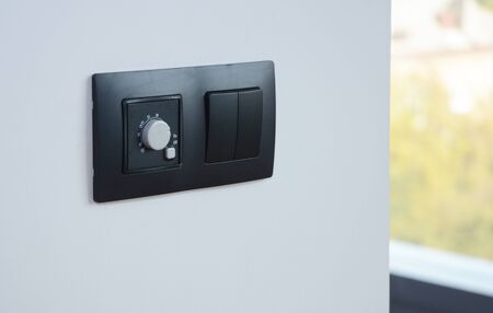 Black light switch on the modern house wall. Socket, air coditioning button,  european power.