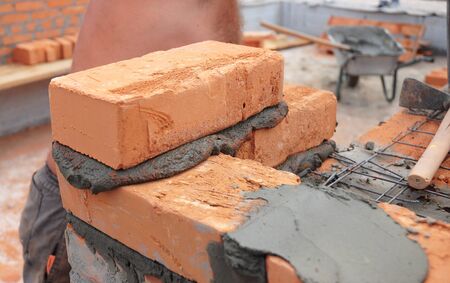 Bricklayer laying brick wall. Close up on bricklayingの写真素材
