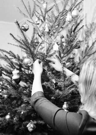 Girl decorating Christmas Tree in the House with Christmas Balls Decoration. Black and White Photoの写真素材