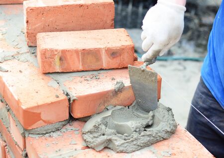 Bricklayers hands in masonry gloves bricklaying new house wall. Bricklaying house wallの写真素材