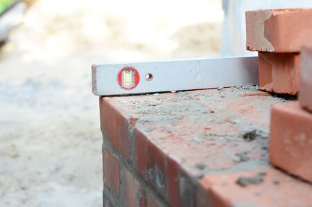A close-up on a sprit level used to level the corner brick courses on a mortar bed while bricklaying...
