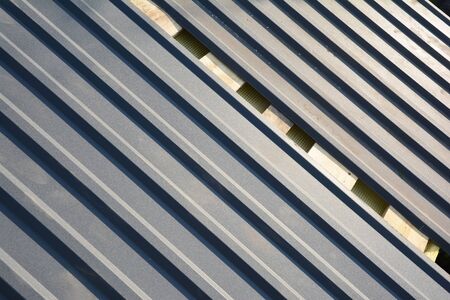 A close-up on stainless steel paint coated gray metal corrugated galvanized roofing sheets, panels...