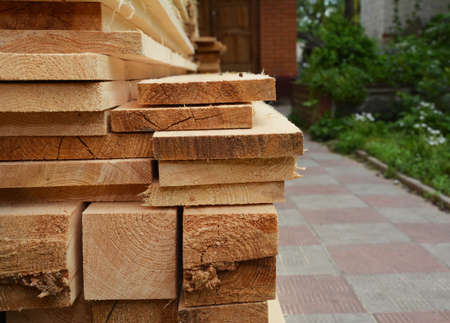 A close up of wooden planks, boards, timber, structural pine beams piled up together in the backyard...