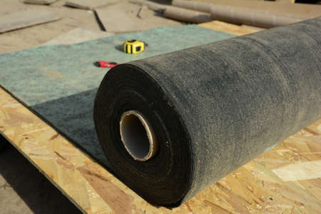 Unrolling waterproofing, water-resistant felt, bituminous roofing underlayment on the roof...