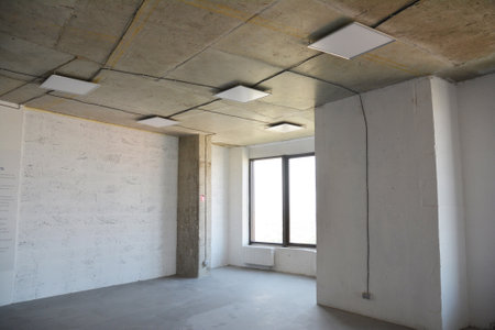 Electrical wiring upgrades: installing electric wiring, cables of a new modern square led ceiling lights and electric outlets, sockets during home renovation.の写真素材