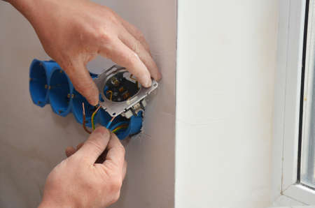 An outlet receptacle, electrical socket, power plug installation. An electrician is installing,...