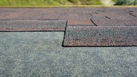 Asphalt roofing shingles installation: A close-up on the architectural asphalt, bitumen roofing shingles installed over a waterproofing underlayment on the roof.の写真素材