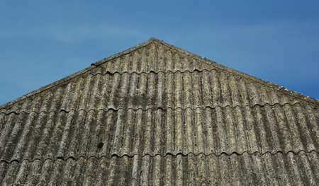 A close-up of an old, run down asbestos roof in bad condition that needs to be repaired against the...