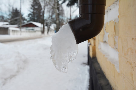 A frozen downpipe, downspout of a rain gutter system. Ice or frozen water in a roof gutter.の写真素材