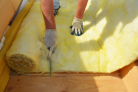 Roofer contractor insulating house roof and cutting mineral wool with a knife. House insulation during roofing construction.の写真素材