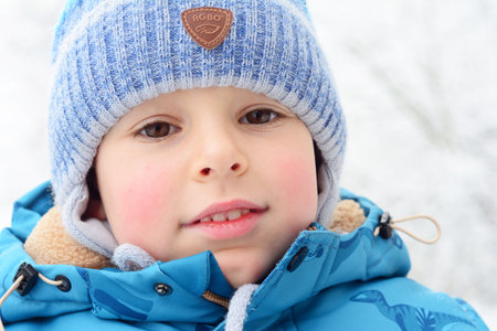 NIZHYN, UKRAINE - November, 15, 2023: Happy little boy with red cheeks and brown eyes in winter frosty and snovy weather.のeditorial素材