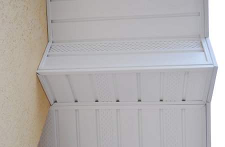 A close-up of a white uPVC soffit, installed along the roofline of the house. Plastic soffit board...