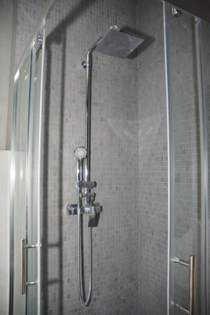 A close-up on a luxury bathroom wall mounted square stainless steel shower rail kit, top spray in a gray modern bathroom.の写真素材