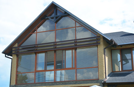 Modern house attic construction with roof guttering and panoramic mansard, attic skylight window. Attic skylight glass wall.の写真素材