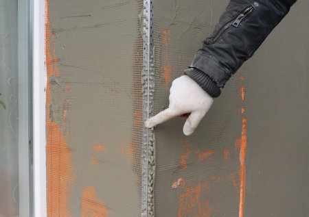 Window angle bead. Close up on applying a coat of plaster, finish over the house window angle bead, reinforcing mesh outdoors.の写真素材
