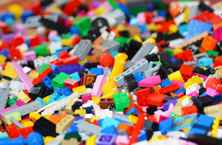 A large pile of colorful plastic toy building blocks used for creative play and learning. Close-up...