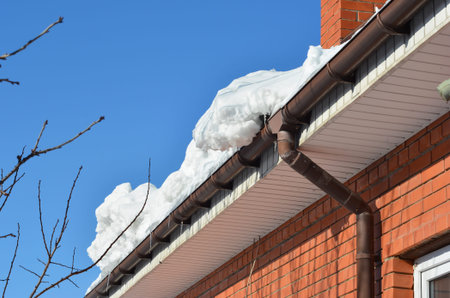 Heavy snow on roof causing gutter damage and collapse risk winter home maintenance