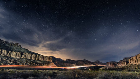bright stars with a highway going through desert mountainsの写真素材