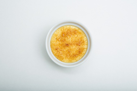 Creme brulee in ceramic bowl on white backgroundの写真素材