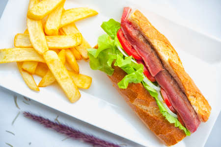 Beef steak sandwich and french fries on white dishの写真素材
