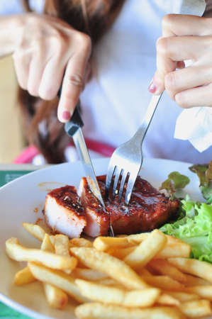 Someone eating grilled steak on white plateの写真素材