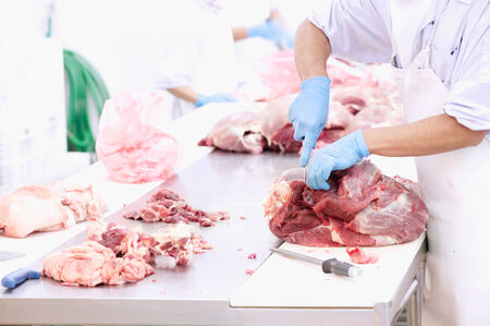 butcher cutting meat on the table in meat industryの写真素材