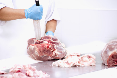 butcher cutting meat on the table in meat industryの写真素材