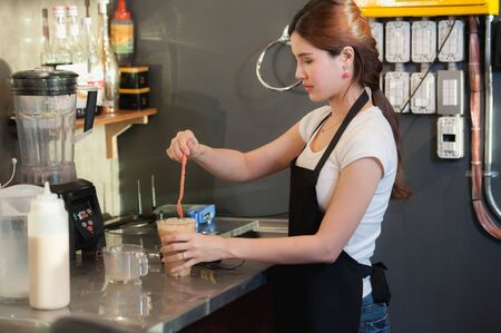 asia beautiful female bartender makes iced coffee on cafeの写真素材