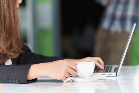 Asia young business woman sitting in cafe with laptop and hot coffee, business conceptの写真素材