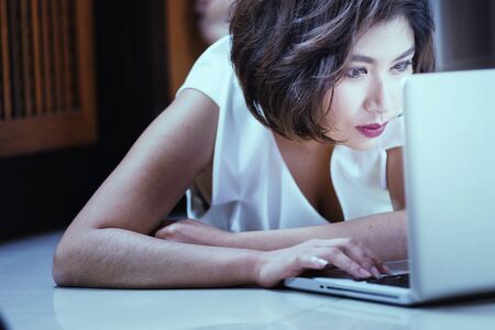 Asia office woman lying on floor with open laptop at home, vintage effectの写真素材