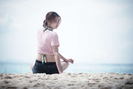 Asia young woman sitting on sandの写真素材