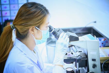 scientist looking through a microscope in a laboratory hospital