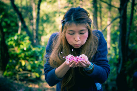 asia woman blowing a flower in your handの写真素材
